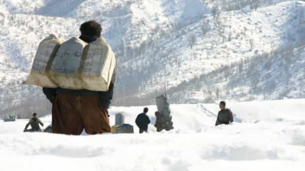 صفی از کولبران در منطقهای کوهستانی با انبوهی برف