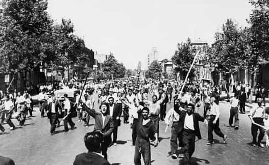 Des manifestants monarchistes qui viennent d'incendier un journal gouvernemental, défilent sur l'Avenue Chah Abbas en plein centre de Téhéran le 26 août 1953. Le Shah d'Iran est rentré d'Italie le 22 août, où il était en exil, après la réussite du coup d'Etat pour restaurer la monarchie. Rioters armed with staves shout slogans, during riots in Tehran, August 1953. On August 19, 1953, democratically-elected Iranian Prime Minister Mohammad Mossadegh was overthrown in a coup orchestrated by the CIA and British intelligence, after having nationalized the oil industry. The Shah Mohammad Reza Pahlavi was re-installed in the primary position of power. Massive protests broke out across the nation, leaving almost 300 dead in firefights in the streets of Tehran. (Photo by - / INTERCONTINENTALE / AFP)