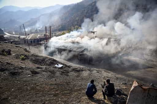 Residents look at burning houses in the village of Charektar outside the town of Kalbajar on November 14, 2020, during the military conflict between Armenia and Azerbaijan over the breakaway region of Nagorno-Karabakh. - Villagers in Nagorno-Karabakh set their houses on fire before fleeing to Armenia ahead of a weekend deadline that will see parts of the territory handed over to Azerbaijan as part of a peace agreement. (Photo by Alexander NEMENOV / AFP)