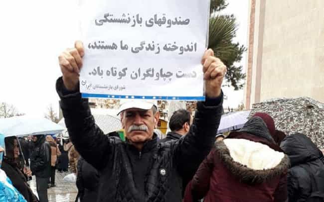 یک بازنشسته معترض کاغذی در دست دارد که بر آن نوشته است «صندوقهای بازنشستگی اندوخته زندگی ما هستند. دست چپاولگران کوتاه باد»د