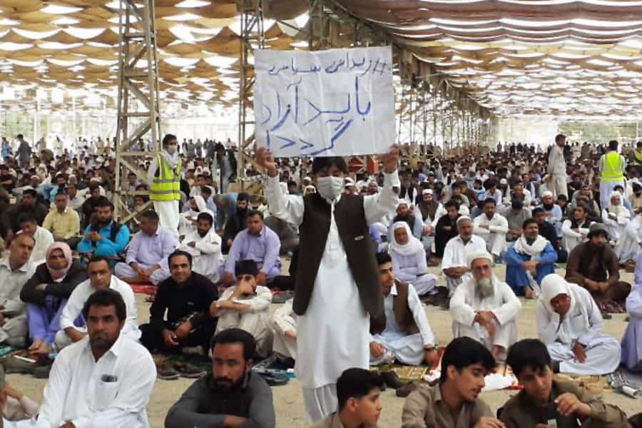 در دست یک معترض بلوچ شعار «زندانی سیاسی آزاد باید گردد» دیده میشود.