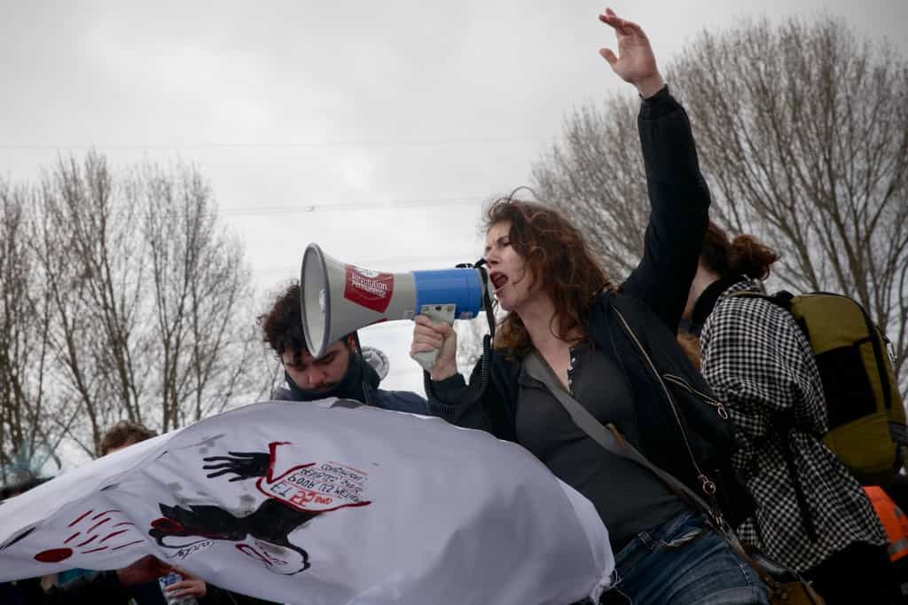 زن معترض با بلندگویی که استیکر «انقلاب مداوم» بر خود دارد، در جمع کارگران اعتصابی توتال‌انرژی در شمال فرانسه، معترضان به اصلاح قانون بازنشستگی، سخن می‌گوید ــ عکس: LOU BENOIST / AFP