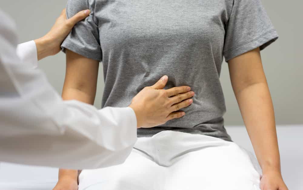 یک پزشک بدن یک زن را معاینه میکند. - عکس از شاتراستاک
