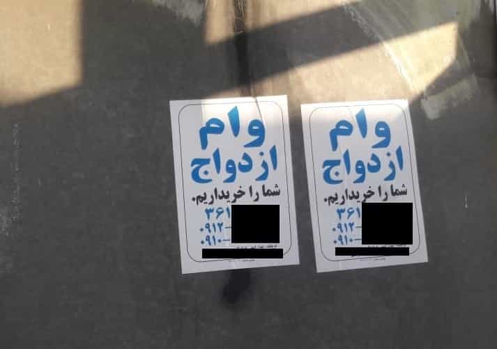 دو آگهی کاغذی خرید وام ازداوج بر یک دیواربا این جمله: «وام ازدواج شما را خریداریم»