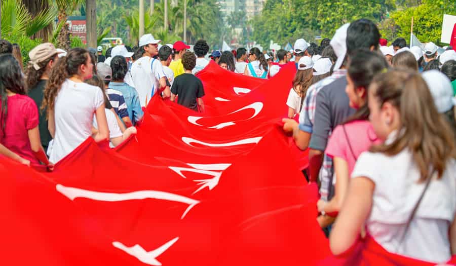 گروهی از دختران و پسران جوان ترکیه پرچم بزرگ این کشور را با خود حمل میکنند. دختران بیحجاباند.
