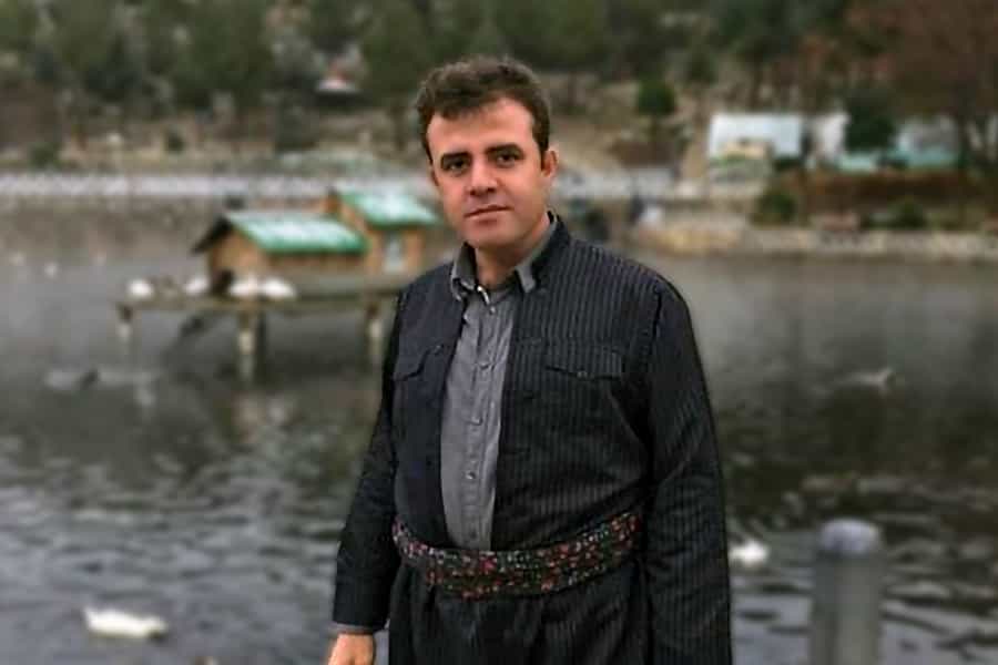 در تصویر یوسف احمدی با لباس کُردی در یک پارک دیده میشود.