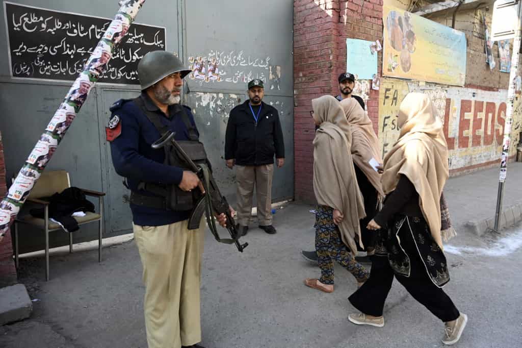 ورود زنان برای رأی دادن در انتخابات سراسری پاکستان در پیشاور در ۸ فوریه ۲۰۲۴، پلیس در خارج از یک مرکز رأی گیری نگهبانی میدهد.