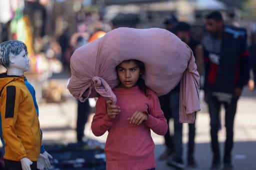 یک دختر فلسطینی با لباس صورتی و یک گونی صورتی رنگ روی سرش. چهرهاش مصمم و کمی مبهوت است.