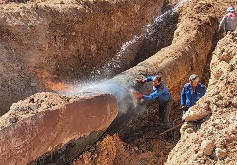 دو نفر در حال تعمیر یک خط لوله گاز بزرگ در ایران