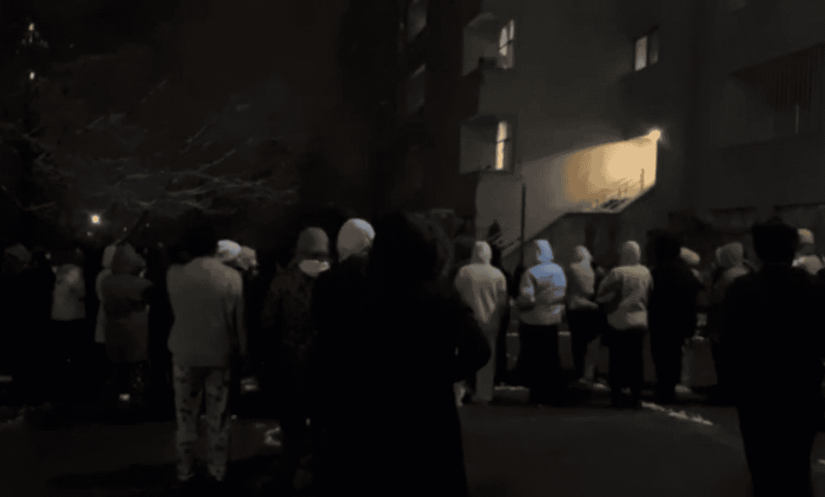 تصویری از تجمع شبانه دانشجویان ساکن خوابگاه دخترانه چمران در تهران. تصویر از پشت حدود ده تا بیست دانشجو را در لباسهای زمستانی نشان میدهد.