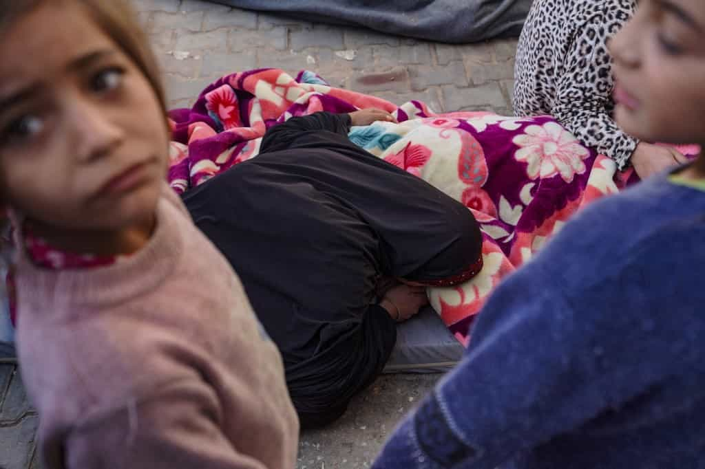 Children look on as a Palestinian woman mourns over the body of a family member in the courtyard of the Al-Aqsa Martyrs Hospital in Deir Al-Balah in the central Gaza Strip, after he was killed in Israeli strikes on the makeshift Al-Mawasi camp for displaced people west of Khan Yunis on March 10, 2024, amid the ongoing battles between Israel and the Hamas militant movement. (Photo by AFP)