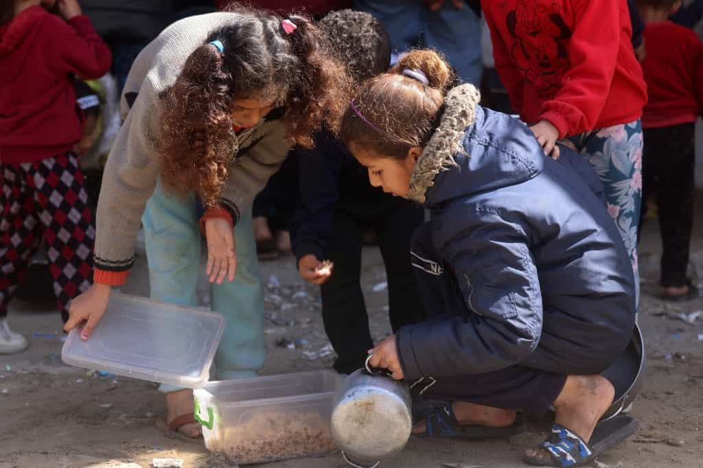 تصویری از چند کودک آواره فلسطینی در نزدیکی یک محل توزیع غذا در رفح در جنوب نوار غزه - ۸ مارس ۲۰۲۴(عکس از MOHAMMED ABED / AFP)