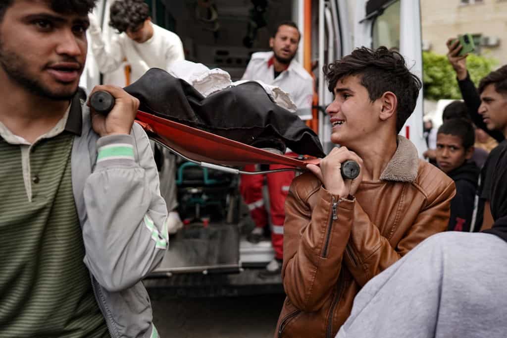 بستگان یک مرد فلسطینی پس از کشته شدن او در بمباران اسرائیل در ۲۸ مارس ۲۰۲۴، جسدش را از آمبولانس به بیمارستان شهدای الاقصی در دیرالبلاح در مرکز نوار غزه منتقل می‌برند. (عکس از خبرگزاری فرانسه)