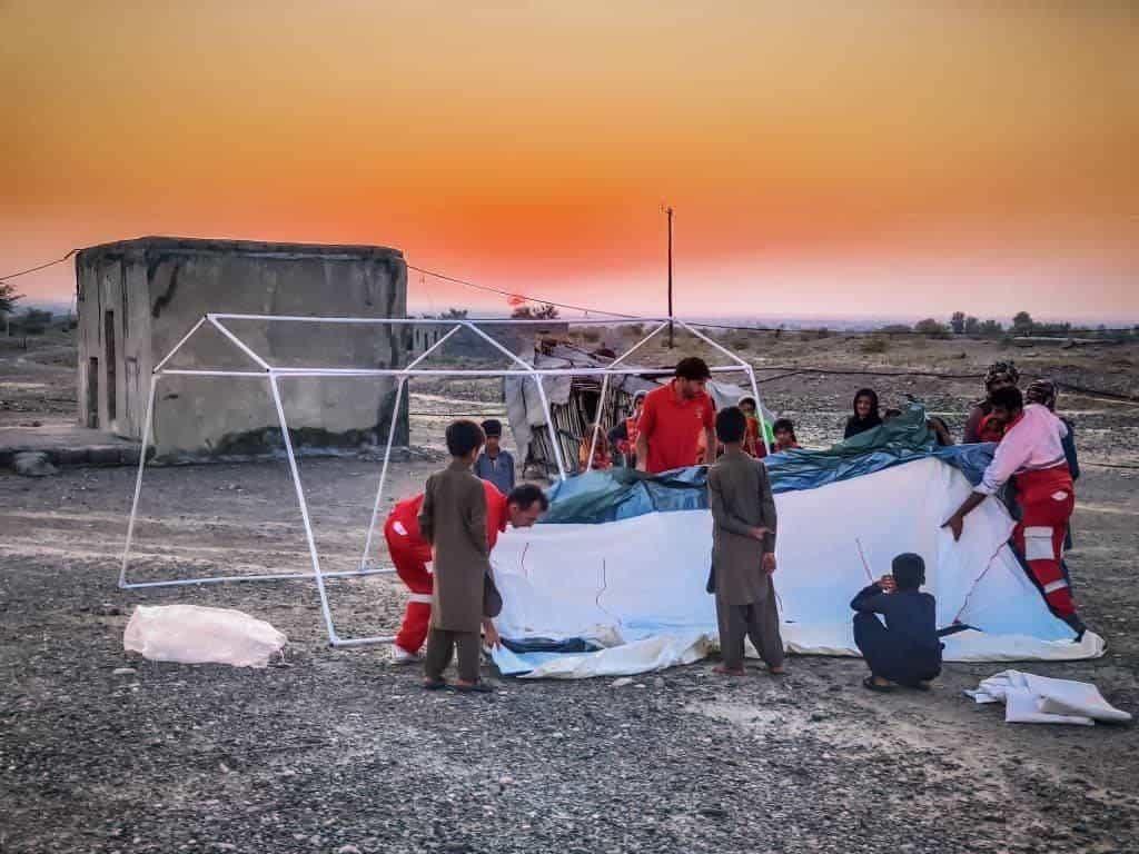 تصویر از هلال احمر ایران که تلاش این سازمان برای برپایی چادر برای آوارگان اقلیمی در سیستان و بلوچستان را نشان میدهد.