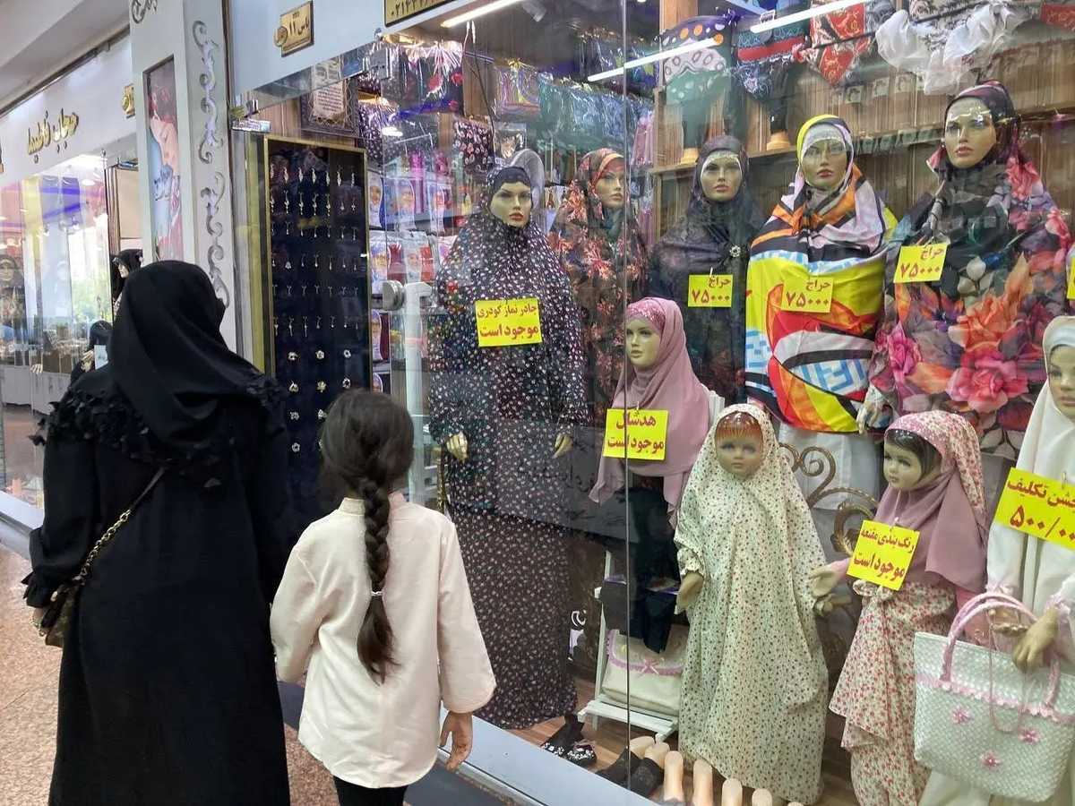 یک مادر و دختر از مقابل ویترین یک مغازه پر از لباسهای اسلامی میگذرند