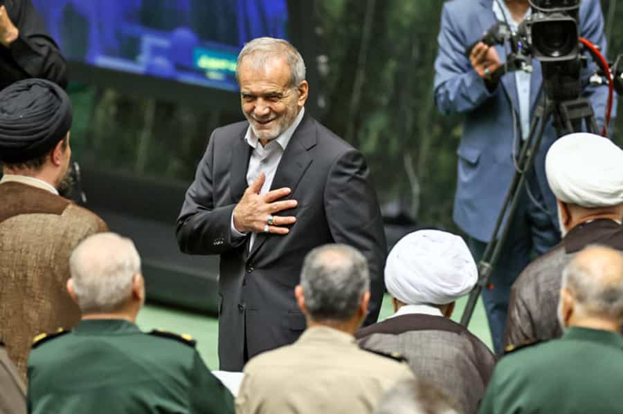 مسعود پزشکیان در حالی که از مقابل چند روحانی و چند فرمانده سپاه پاسداران عبور میکند دست خود را روی سینهاش گذاشته و با لبخندی بر لب تشکر میکند.