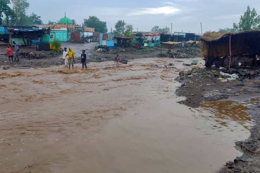 در زیر باران، رودخانهای از کنار چند آلونک شبیه به حلبیآباد میگذرد و چند جوان رنگینپوست در کنار آن ایستادهاند. هوا هم ابری است.