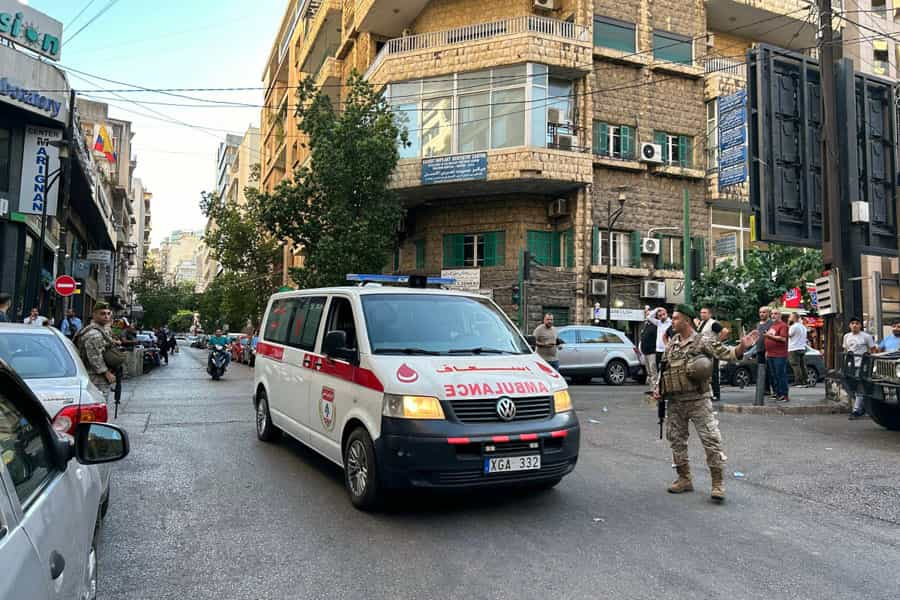 یک آمبولانس در خیابانی در بیروت در حال حرکت است و سربازان در اطراف آن جهت را نشان می‌دهند.