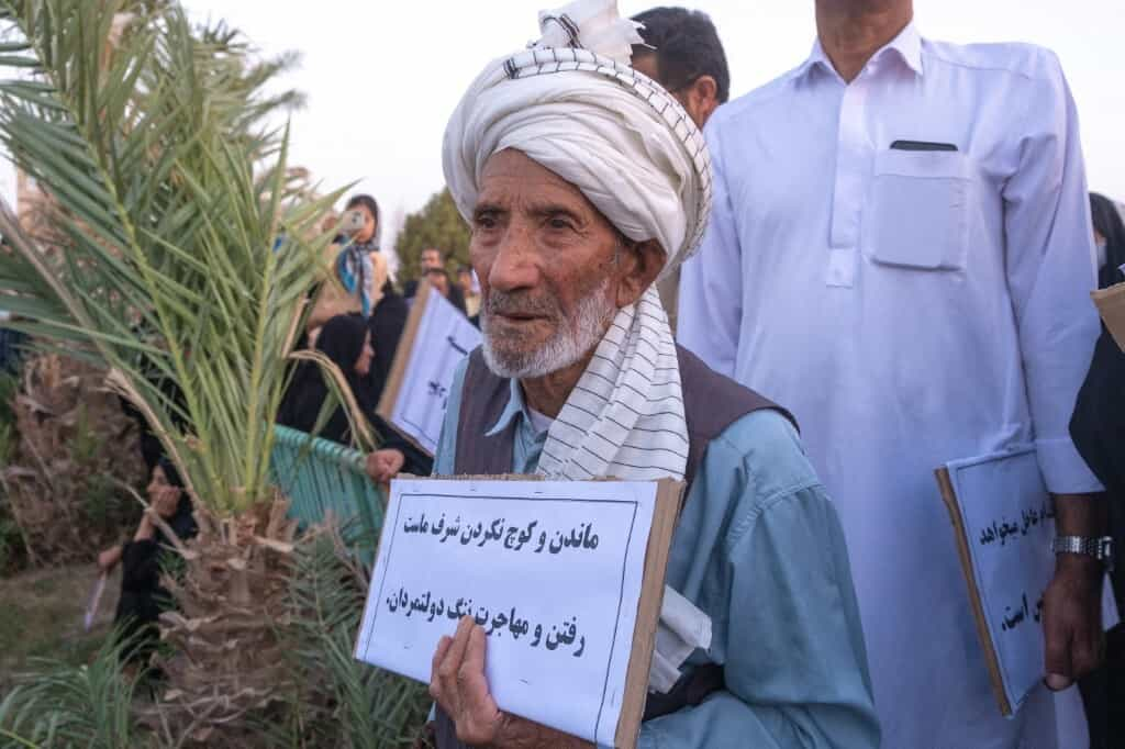 تصویر خبرگزاری فرانسه از یک فرد بومی شرق ایران که نوشته‌ای اعتراضی به دست گرفته است: «ماندن و کوچ نکردن شرف ماست، رفتن و مهاجرت ننگ دولتمردان»