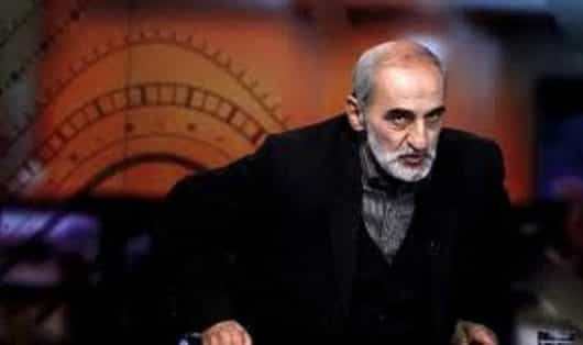 تصویر حسین شریعتمداری در حال بلندشدن از صندلی با حالت تهدیدآمیز