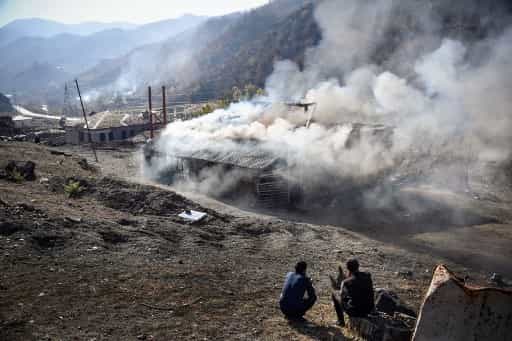 Residents look at burning houses in the village of Charektar outside the town of Kalbajar on November 14, 2020, during the military conflict between Armenia and Azerbaijan over the breakaway region of Nagorno-Karabakh. - Villagers in Nagorno-Karabakh set their houses on fire before fleeing to Armenia ahead of a weekend deadline that will see parts of the territory handed over to Azerbaijan as part of a peace agreement. (Photo by Alexander NEMENOV / AFP)
