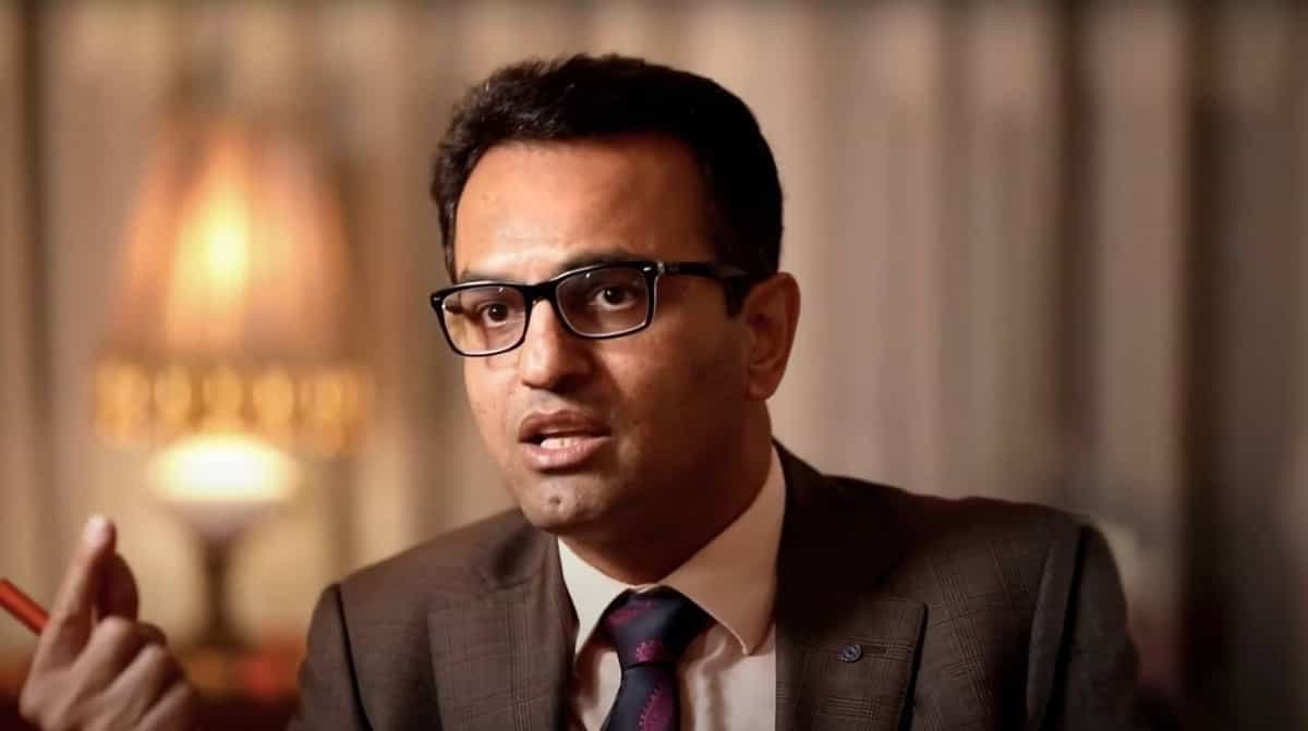 سعید دهقان، وکیل حقوق بشر، با کت قهوهای، پیرهن سفید، و کراوات مشکی، عینک طبی مستطیلی در حال صحبت کردن