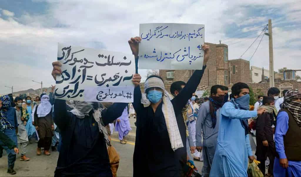 تظاهرات زاهدان: دو تن از معترضان کاغذنوشتههایی در دست دارند که بر یکی از آنها نوشته شده نه سلطنت نه رهبری، آزادی و برابری و دیگری؛ نگوییم براندازی مرکزگرایی بگوییم فروپاشی کنترل شده.
