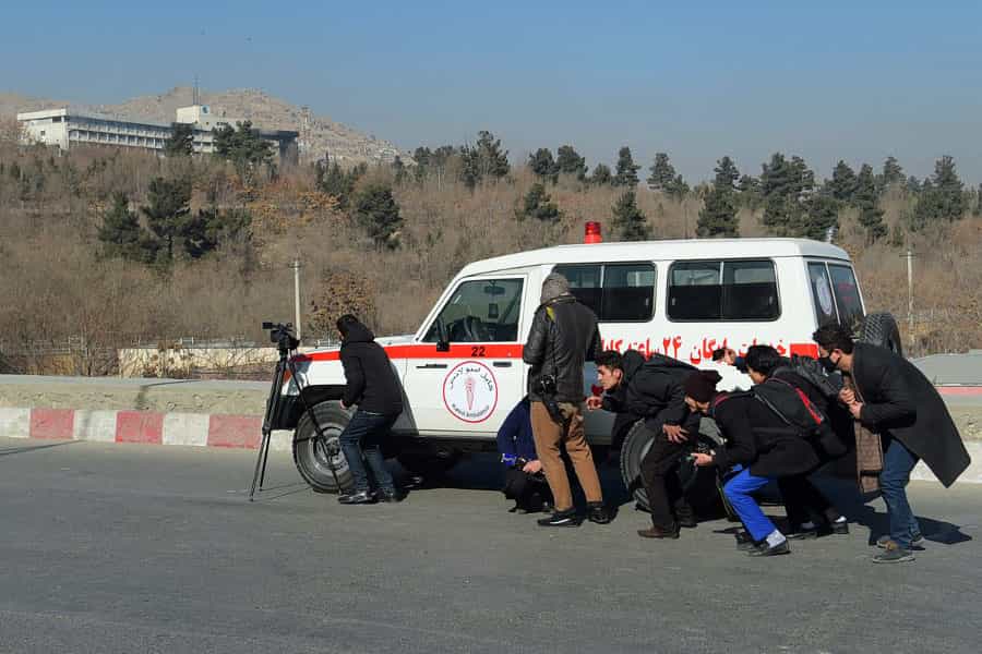 در عکس چند عکاس و خبرنگار افغانستانی نشان داده میشود که پشت آمبولانسی پناه گرفتهاند.
