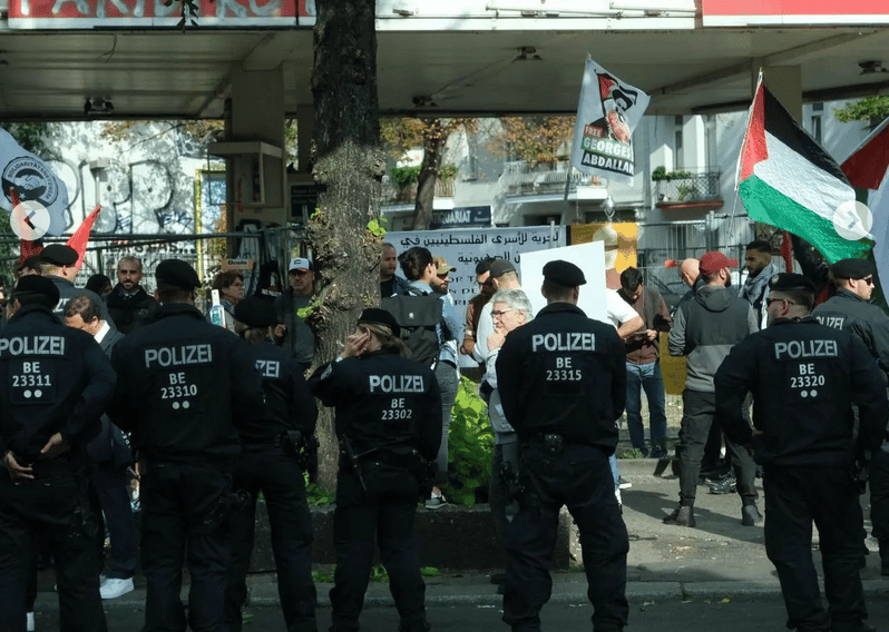 پلیس راه را بر حامیان فلسطین بسته است. یکی از آنان پرچم فلسطین را بر دوش دارد. برلین- اکتبر ۲۰۲۳
