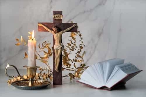 پسزمینه سفید، از راست به چپ کتاب مقدس، صلیب و مسیح به صلیب کشیده، شمع