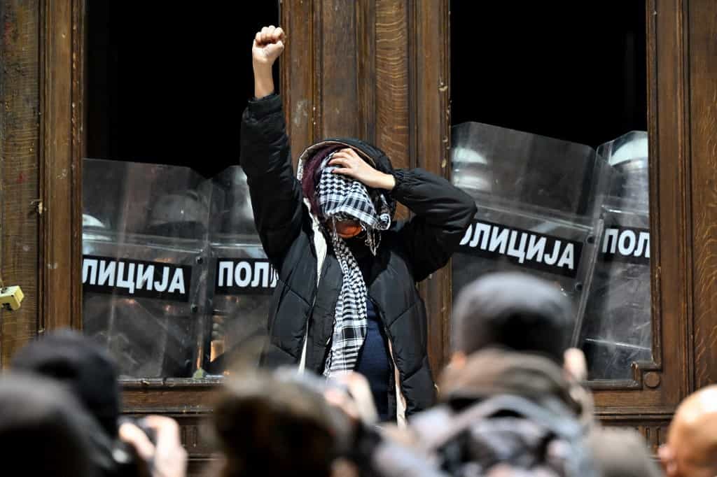یک معترض در برابر ماموران پلیس در ورودی ساختمان شورای شهر بلگراد در تظاهراتی علیه تقلب در انتخابات پارلمانی و محلی در صربستان- ۲۴ دسامبر ۲۰۲۳