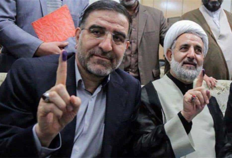 مجتبی ذوالنوری و احمد امیرآبادی فراهانی نمایندههای قم در زمان رایگیری برای انتخابات مجلس شورای اسلامی در سال ۱۳۹۸ انگشتهای جوهریشان را نشان میدهند