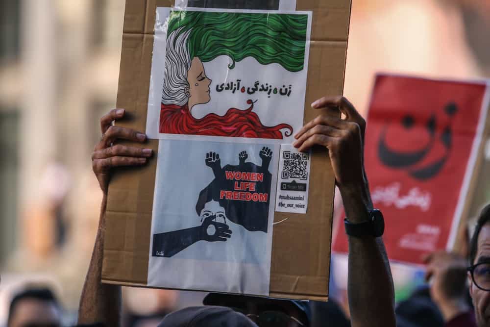 تصویر تزئینی از شاتر استاک یک راهپیمایی ضد جمهوری اسلامی را در شهر ونکوور کانادا نشان میدهد که در آن یک نفر تابلوی «زن، زندگی، آزادی» را به دو زبان فارسی و انگلیسی در دست دارد.