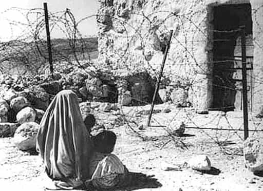 تصویر تاریخی خبرگزاری فرانسه از ۱۹۴۸ میلادی، یک زن پناهنده و فرزندش را نشان میدهد که جلوی خانه سابقشان نشستهاند. خانه با سیم خاردار از آنها جدا شده است.