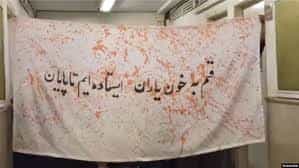 روی پارچهای نوشته شده: «قسیم به خون یاران، ایستاده ایم تا پایان»
