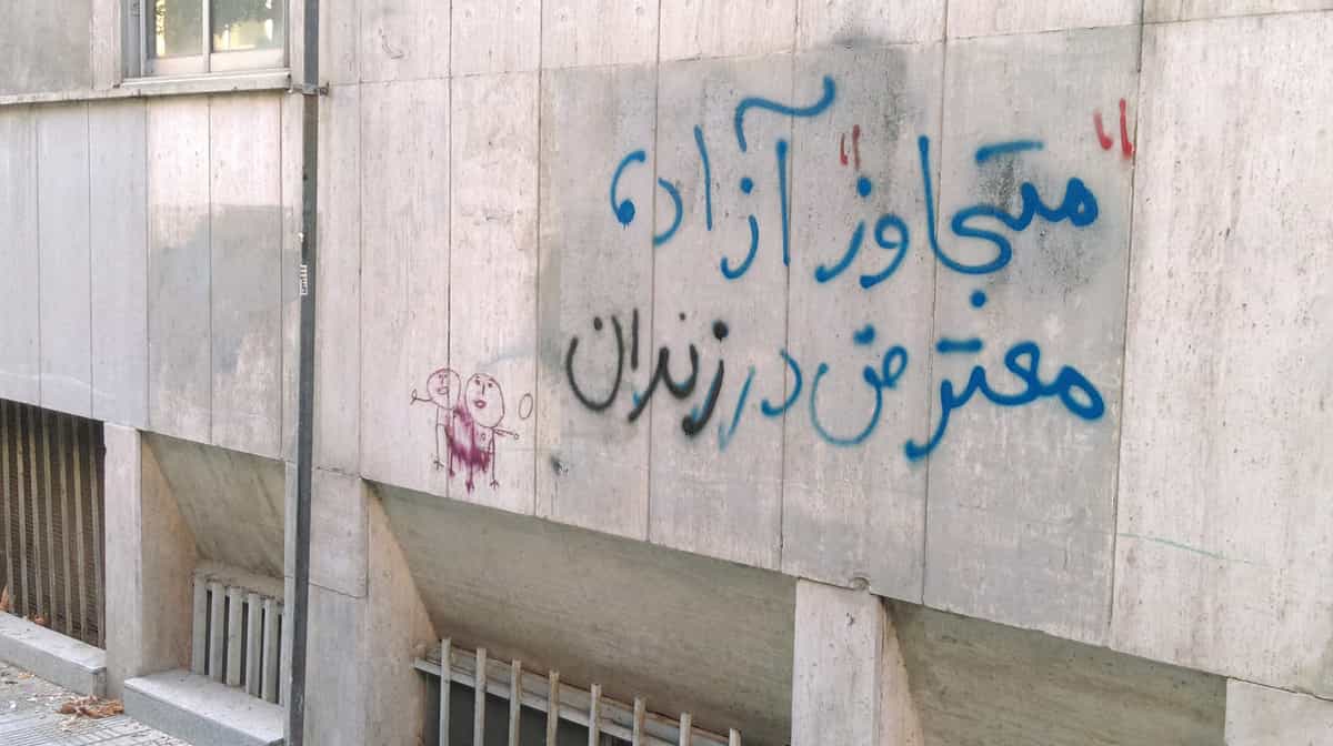روی دیوار نوشته شده: «متجاوز آزاد، معترض در زندان»
