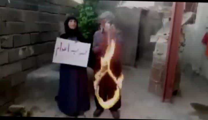 زن و مردی در حیاط خانهای نیمهساخته زن نوشتهی نه به اعدام در دست دارد و مرد ظناب داری را آتش زده است