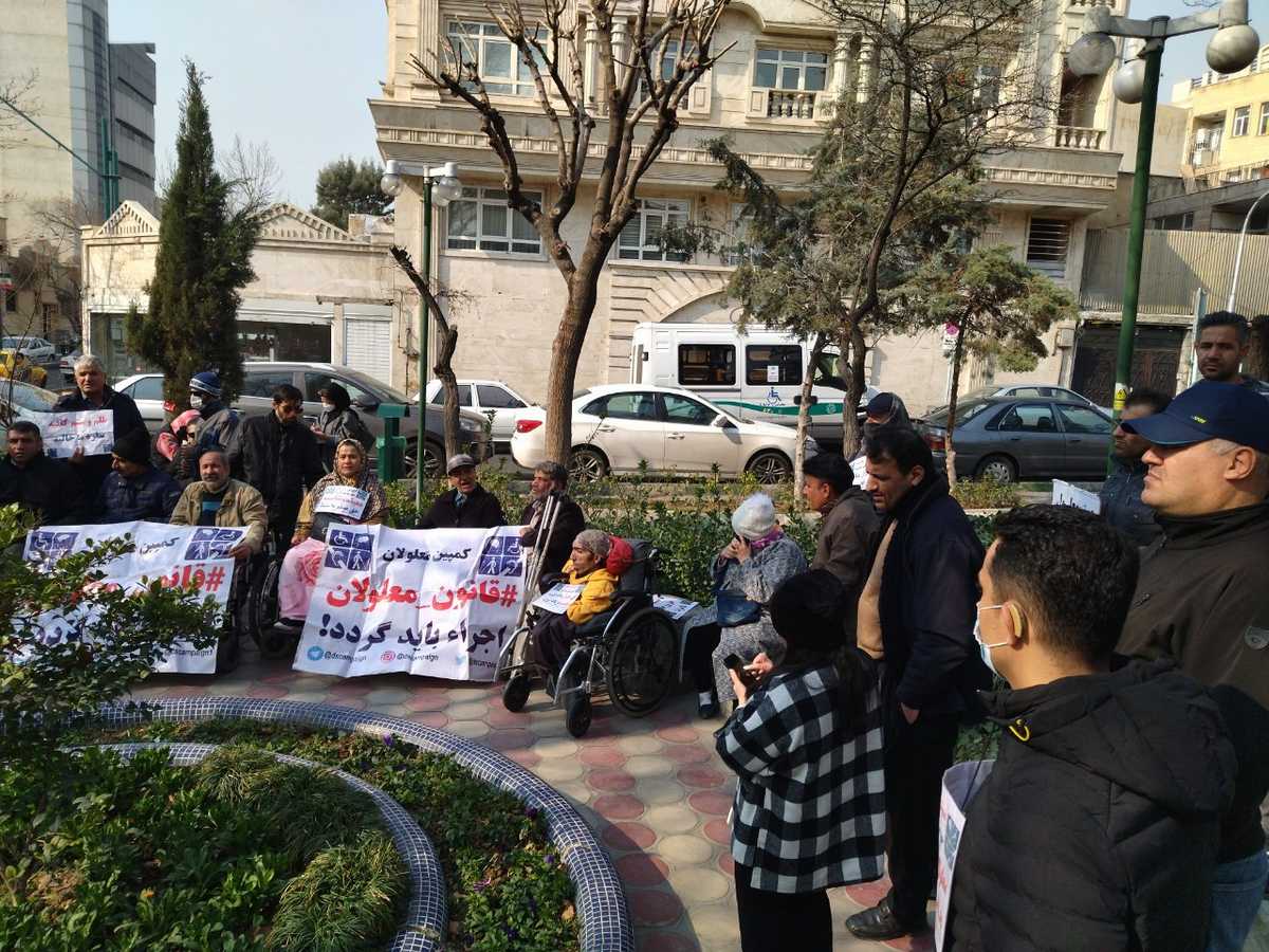 تصویری از تعدادی از معترضان معلول در پارک استور. برخی پلاکارد در دست دارند