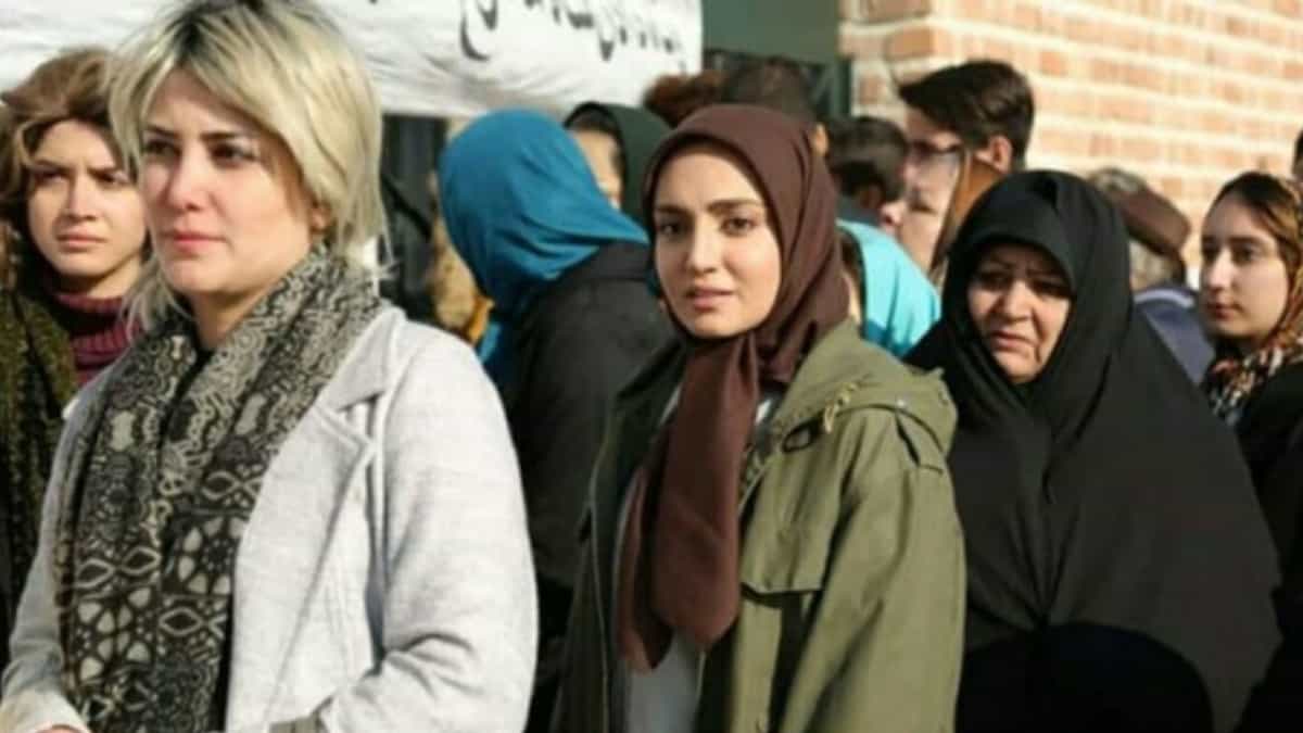 صحنهای از زنانی که صف بستهاند. یکی از آنها کلاهگیس بلوند به سر دارد، چند زن با مانتو و روسری دیده میشوند و یک زن با چادر