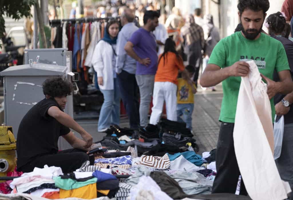 تصویری از دو مرد دستفروش که لباس می‌فروشند