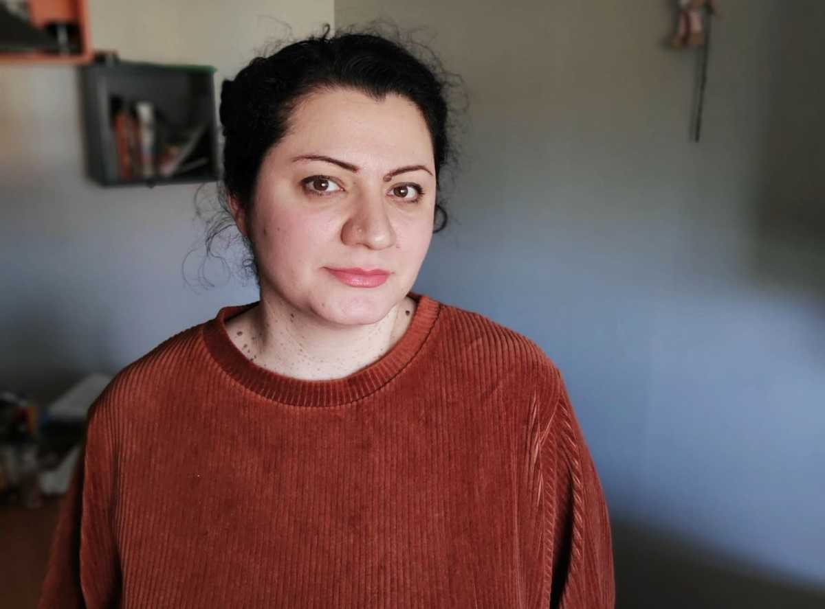 تصویری از کتایون کشاورزی. زنی که حدودا ۴۰ ساله است. پیراهن بافتنی قرمز آجری پوشیده و به دوربین نگاه می کند