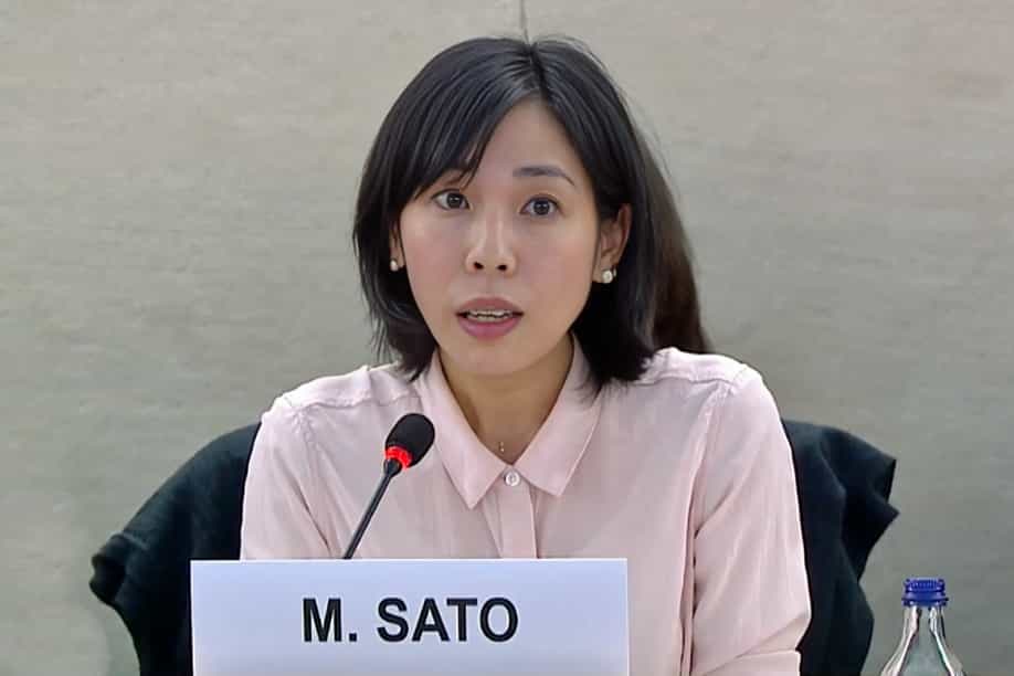 مای ساتو (Mai Sato) حقوقدان ژاپنی و گزارشگر ویژه سازمان ملل در امور حقوق بشر ایران هنگام سخنرانی پشت میکروفون. جلوی او نامش به لاتین نوشته شده است.