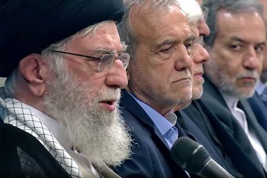 نمای نزدیک از چهره‌های علی خامنه‌ای و سپس مسعود پزشکیان و دیگر اعضای کابینه دولت چهارهم از نیم‌رخ. خامنه‌ای در حال سخنرانی است.