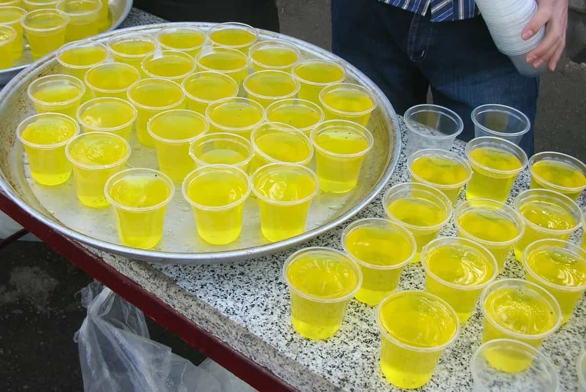 دو سینی مملو از لیوان‌های یکبار مصرف پر شده از شربت نذری در ماه محرم