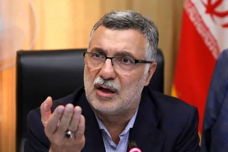 محمدرضا ظفرقندی، در حال صحبت دست خود را بلند کرده است. پشت سر او پرچم جمهوری اسلامی دیده میشود.