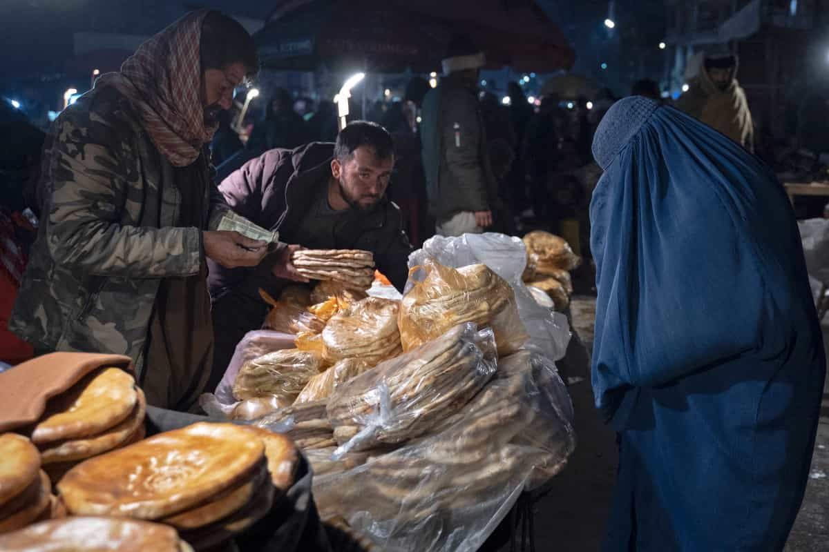 در تاریکی شب دو مرد روی یک دکه نان می‌فروشند و یک زن با برقع از آن‌ها نان می‌خرد