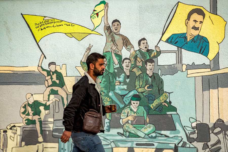 مردی از کنار یک نقاشی دیواری که حامیان نیروهای دموکراتیک سوریه (SDF) را به تصویر کشیده است، می‌گذرد
