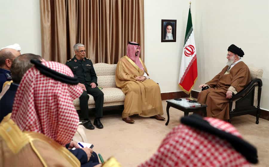 خالد بن سلمان در کنار علی خامنهای نشسته و در اطراف او مقامات ایرانی و سعودی دیده میشوند.