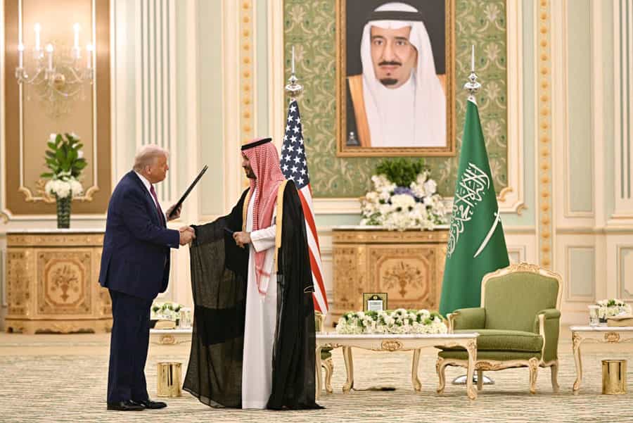دونالد ترامپ، رئیسجمهور آمریکا در حالیکه متن توافقنامهای را در دست دارد با محمد بن سلمان، ولیعهد عربستان سعودی دست داده است.