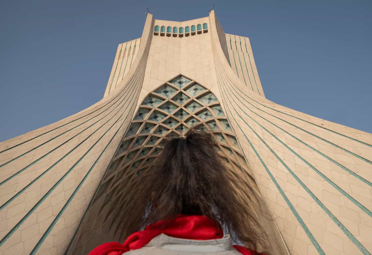یک زن جوان ایرانی در حالی که در یک کنسرت زنده در غرب تهران، ایران، در ۲۵ ژوئن ۲۰۲۵، همزمان با آتش‌بس بین ایران و اسرائیل، در مقابل بنای یادبود آزادی ایستاده است.